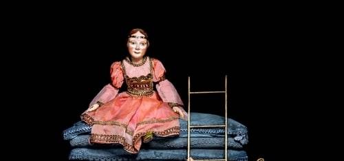 Spielfigur der Prinzessin aus einen hohen Stapel Matrazen sitzend