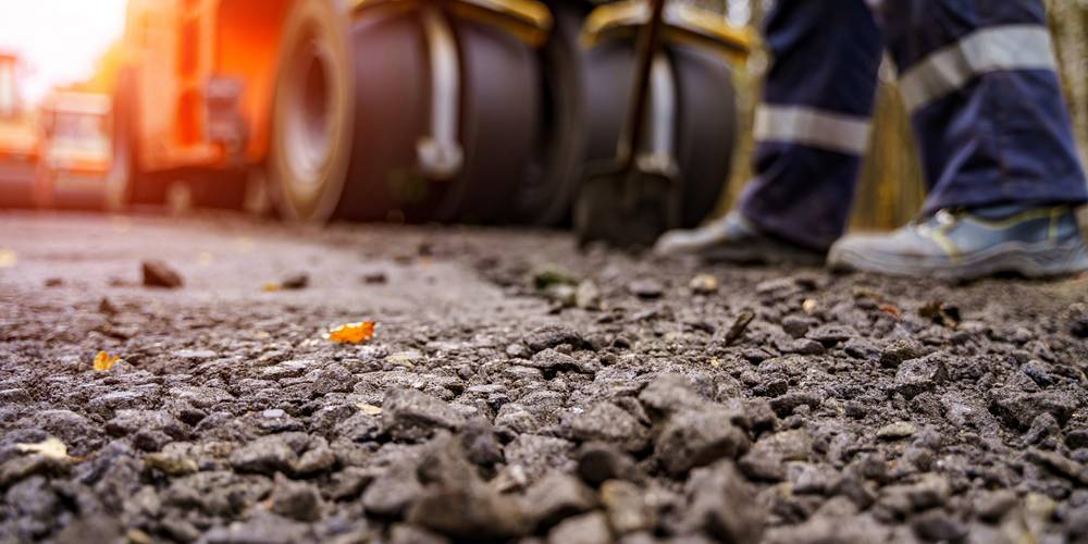 Asphalt und Baufahrzeuge im Hintergrund