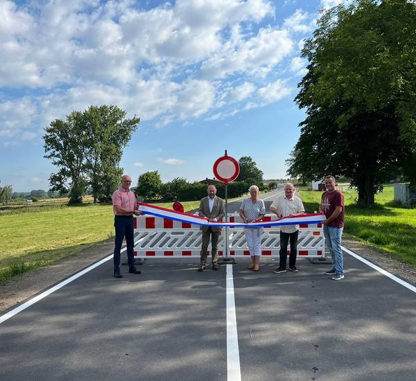 Dezernent Romuald Bittl sowie Vertreter des Landkreises und der beteiligten Firmen durchschneiden das Band zur Freigabe der Straße.